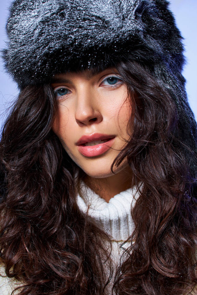 gyönyörű fiatal nő szőrös kalap és fehér ruha pózol szürke háttér, téli divat - Fotó, kép