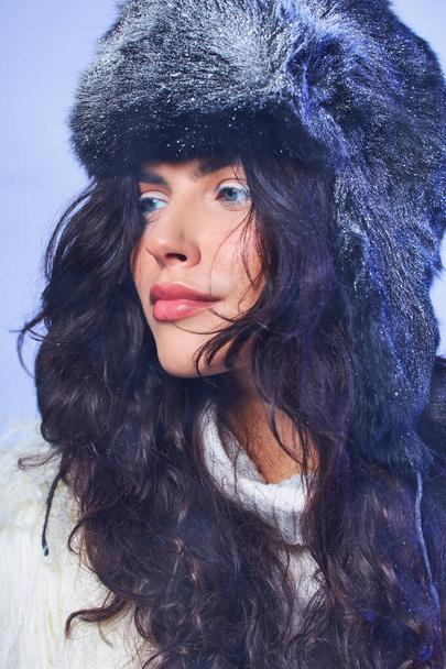 téli szépség, fiatal nő téli kalap hó és fehér pulóver szürke háttér, hűvös levegő - Fotó, kép