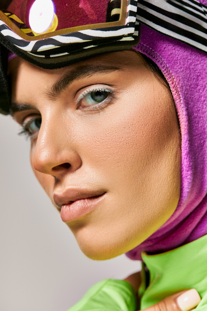 gros plan de la femme en vêtements de ski d'hiver avec cagoule sur la tête regardant caméra sur gris, portrait - Photo, image