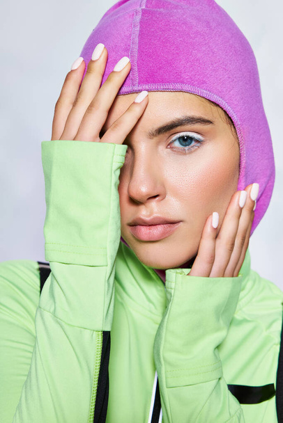 portrait of beautiful woman with blue eyes posing in warm ski mask and active wear on grey backdrop - Photo, Image