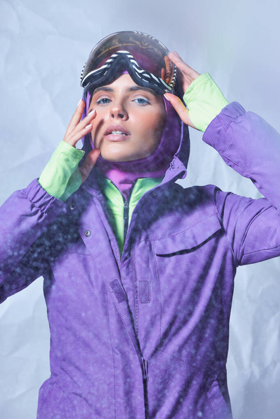 kaunis nainen parvekkeella ja talvitakki yllään ski googles harmaalla taustalla, luminen päivä - Valokuva, kuva