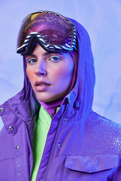 mulher bonita em máscara de esqui e googles vestindo jaqueta quente no fundo roxo, estilo de inverno - Foto, Imagem