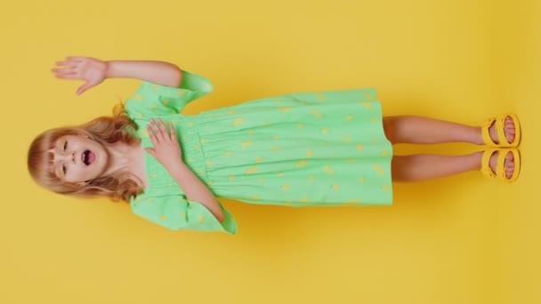 I swear to be honest. Sincere responsible child girl kid raising hand to take oath, promising to be honest tell truth be polite, keeping hand on chest. Preteen children on yellow background. Vertical - Footage, Video