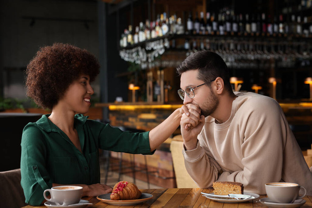 International relationships. Handsome man kissing her girlfriend's hand in cafe - Fotografie, Obrázek