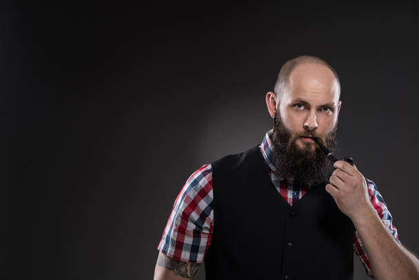 Muscular tatuado hombre fuma una pipa
 - Foto, imagen