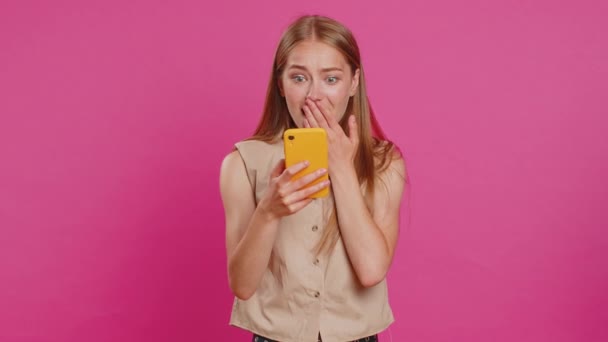 Happy excited joyful woman girl use smartphone typing browsing shouting say wow yes found out great big win, good news, lottery goal achievemen, celebrating success, winning game on pink background - Footage, Video