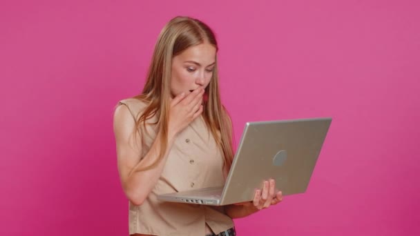 Overjoyed happy young woman with laptop scream in delight raise hand in triumph winner gesture celebrate success win victory money in lottery. Excited girl get online good news on pink background - Footage, Video
