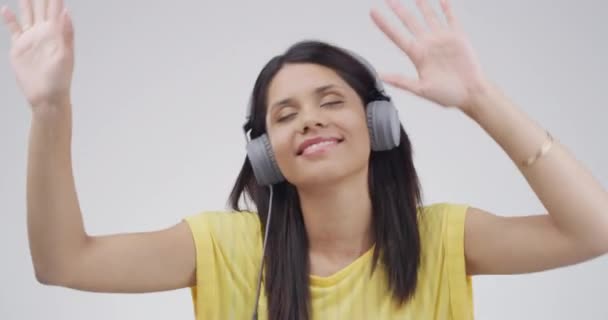 Dance, music and face of excited woman in studio listening to audio, streaming song or radio. Happy, dancing and portrait of person with headphones for energy, subscription and fun on gray background. - Footage, Video