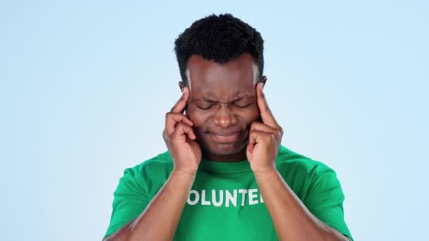 Sick, volunteer and black man with a headache, stress and health issue on a blue studio background. African person, charity worker and model with a migraine, ngo and medical problem with tension. - Footage, Video