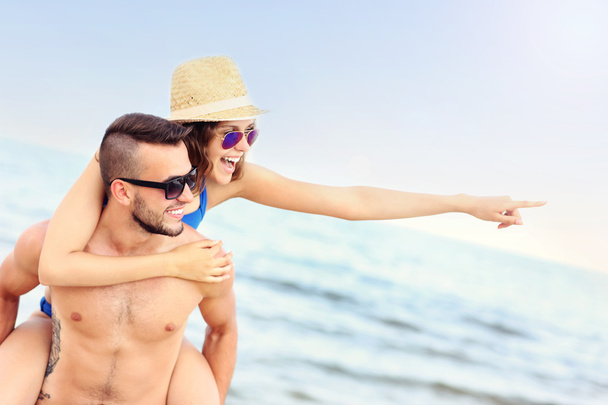junges Paar zeigt auf etwas am Strand - Foto, Bild