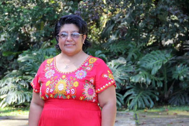 Übergewichtige brünette Latina erwachsene Frau in ihren 50ern ist glücklich und stolz auf ihre Wurzeln in traditionellen mexikanischen bestickten Kleidern - Foto, Bild