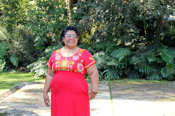 Υπερβολική μελαχρινή Λατίνα ενήλικη γυναίκα στα 50 της είναι χαρούμενη και περήφανη για τις ρίζες της που φοράει παραδοσιακό μεξικάνικο κεντημένο φόρεμα. - Φωτογραφία, εικόνα