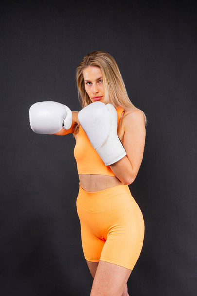 boxeur femme en gants de formation sur un fond de studio jaune et sombre - Photo, image