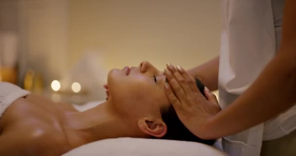 Relax, skincare and woman with facial massage at spa in zen, physical therapy on bed with candles at resort. Face of calm female person sleep in rest with body care for health and wellness at salon - Video