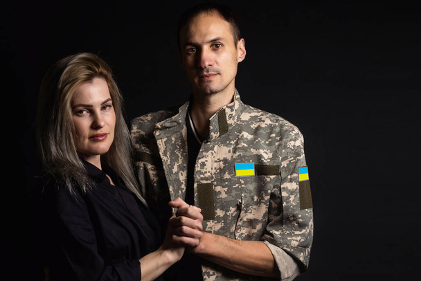 Feliz pareja ucraniana que se conocieron después de la guerra. Un militar de uniforme abraza a su feliz esposa. - Foto, Imagen