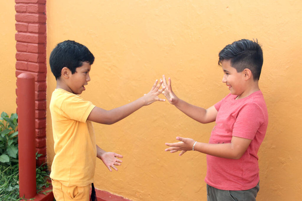 9-jarige Latino kinderen spelen schaar, papier of steen voor de lol zonder videospelletjes - Foto, afbeelding