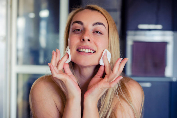 Una foto stile di vita di una bella donna che pulisce delicatamente il viso, mostrando la sua routine di cura della pelle a casa - Foto, immagini