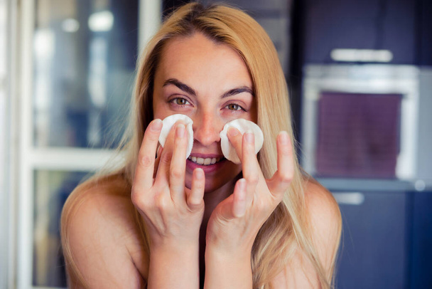 Une photo de style de vie d'une belle femme nettoyant doucement son visage, montrant sa routine de soins de la peau à la maison - Photo, image