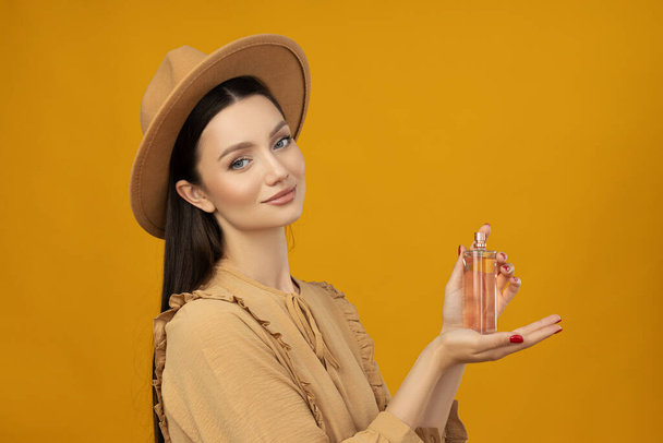 Attractive girl in a hat with perfume in her hand - Photo, Image