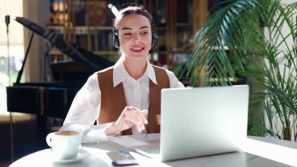 Trendy restaurant owner efficiently communicates via video call on her laptop, engaging in an online chat with business partners, modern long distance communication in a beautifully designed interior. - Footage, Video