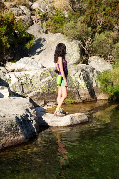Mujer de lado en una roca viendo el río
 - Foto, imagen