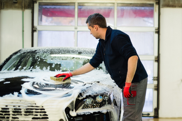Arbeiter wäscht Luxusauto mit Schwamm in Waschanlage  - Foto, Bild