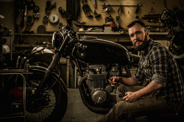 Mechanic building vintage style cafe-racer motorcycle  in custom garage - Photo, Image