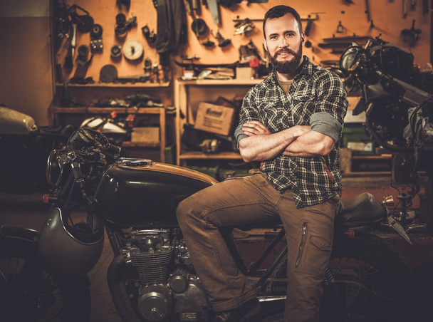 ライダーと税関のガレージでビンテージ スタイルのカフェ レーサー バイク  - 写真・画像