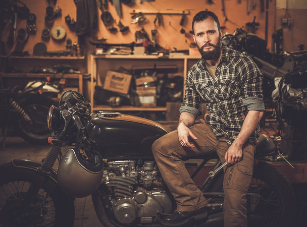 Rider ja hänen vintage tyyli kahvila-racer moottoripyörä tulli autotallissa
  - Valokuva, kuva