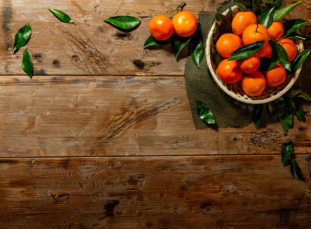 Panier avec de savoureuses mandarines sur une table en bois
  - Photo, image