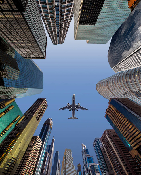 Самолет пролетает над деловыми небоскребами финансового центра. Концепция путешествий, экономики, грузов, транспорта. Вид с низкого угла - Фото, изображение