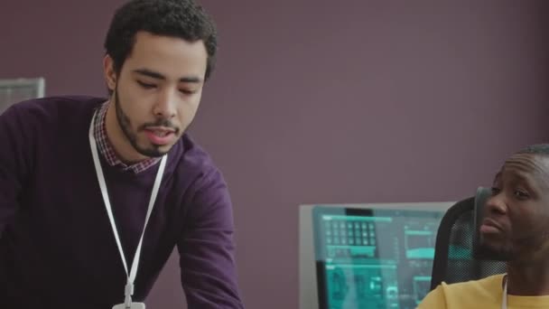 Due ingegneri software multietnici professionisti stanno discutendo mentre sviluppano una nuova applicazione in ufficio - Filmati, video