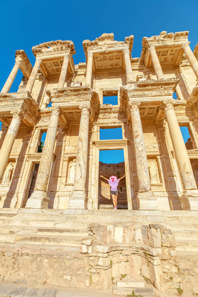 Uma mulher turística fica admirada diante da grandeza da Biblioteca de Celso em Éfeso, Turquia, com seus olhos traçando os intrincados detalhes da antiga fachada banhada pela luz solar suave. - Foto, Imagem