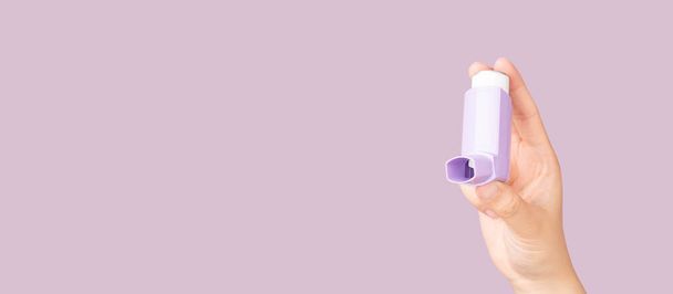 Manos sosteniendo el inhalador de asma sobre fondo morado. El producto farmacéutico se utiliza para tratar la inflamación pulmonar y prevenir el ataque de asma en pacientes con asma o EPOC. Salud y concepto médico. - Foto, Imagen