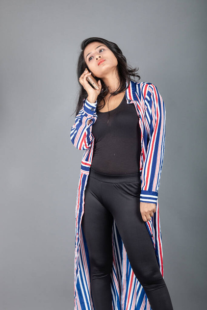 Beautiful woman wearing black leggings, black top and red, blue, white striped tunic. Female model in casual wear, advertisement shot. - Photo, Image