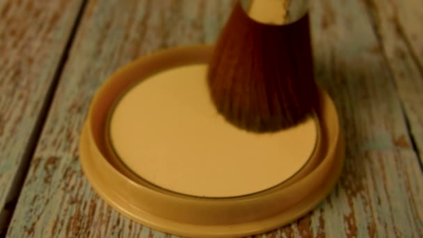 El cepillo de maquillaje se mueve sobre la caja de polvo. Un cepillo se utiliza para recoger el polvo de maquillaje. Aplicar polvo en la cara. Maquillaje - Imágenes, Vídeo