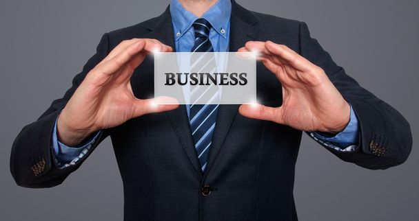 Empresário detém cartão branco com sinal de negócio. Isolado em vários fundos (cinza, azul, escritório, branco) - Imagem stock
 - Foto, Imagem