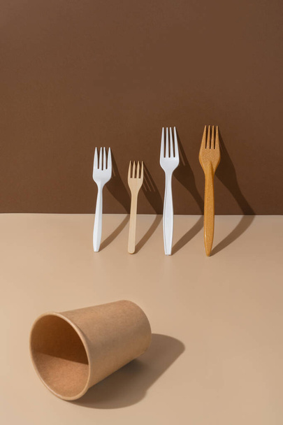 Eco friendly différentes fourchettes et une tasse vide sur un fond beige et brun.. Biodégradable, alternative composable au plastique. - Photo, image