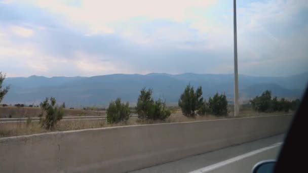 Sininen taivas ja vuoret nähtynä auton sivuikkunasta ajon aikana Georgiassa. Auto kulkee pitkin tietä, ja otan kuvia kaukaisista vuorista ja maatalouspelloista.. - Materiaali, video