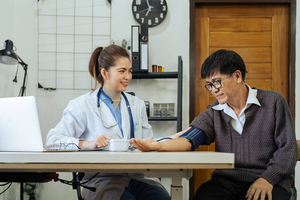 Doctor take care of elderly by helping to check their blood pressure. - Photo, Image