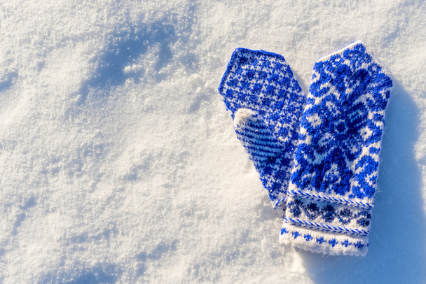 warm woolen mittens with beautiful pattern lying in the snow - Fotoğraf, Görsel
