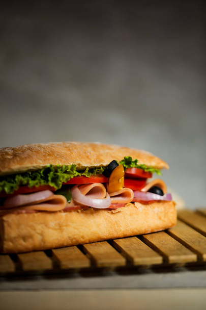 Ciabatta Smoked Ham Sandwich isolated on wooden with mayonnaise dip and french fries bucket board side view of italian fast food on grey background - Photo, Image