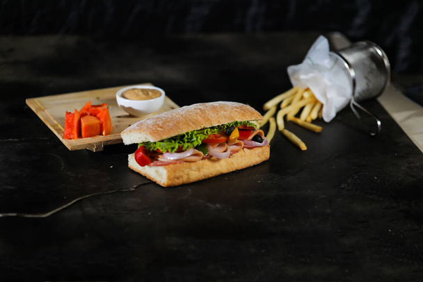 Sandwich au jambon fumé Ciabatta isolé sur bois avec trempette à la mayonnaise et plateau seau frites vue latérale du fast food italien sur fond gris - Photo, image