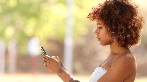 νεαρή Αφροαμερικανή γυναίκα που χρησιμοποιεί smartphone σε εξωτερικούς χώρους - Πλάνα, βίντεο