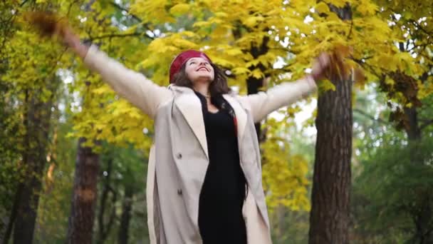 Onnellinen nuori nainen syksyllä jättää ulkona puistossa puita, vapautta ja hauskaa luonnossa. Onnellinen innoissaan tyttö lämpimissä vaatteissa metsässä. - Materiaali, video