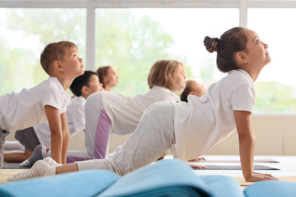Gruppe kleiner Kinder übt Yoga in der Turnhalle - Foto, Bild