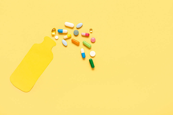 Butelka papierowa i różne tabletki na żółtym tle - Zdjęcie, obraz