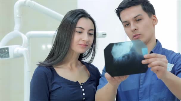 Sorriso saudável e bonito. Dentista mostra um paciente raios-x dos dentes no consultório odontológico, enquanto o paciente eo médico mostrando polegar para cima e olhando para a câmera com o dentista
 - Filmagem, Vídeo