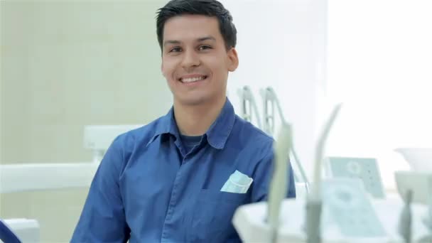 Portret udane stomatologa. Dentysta, uśmiechając się do kamery przed podjęciem pacjent wśród urządzeń stomatologicznych - Materiał filmowy, wideo