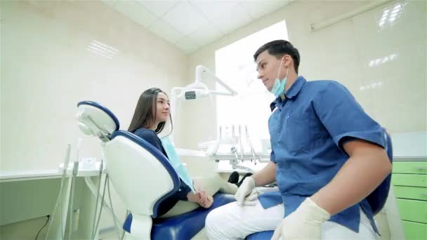 Στις διαβουλεύσεις νέους επιτυχείς οδοντιάτρου. Ο οδοντίατρος μιλάει στον ασθενή, στη συνέχεια, να περιστρέψετε μαζί και να δείξει τους αντίχειρες μέχρι την κάμερα - Πλάνα, βίντεο